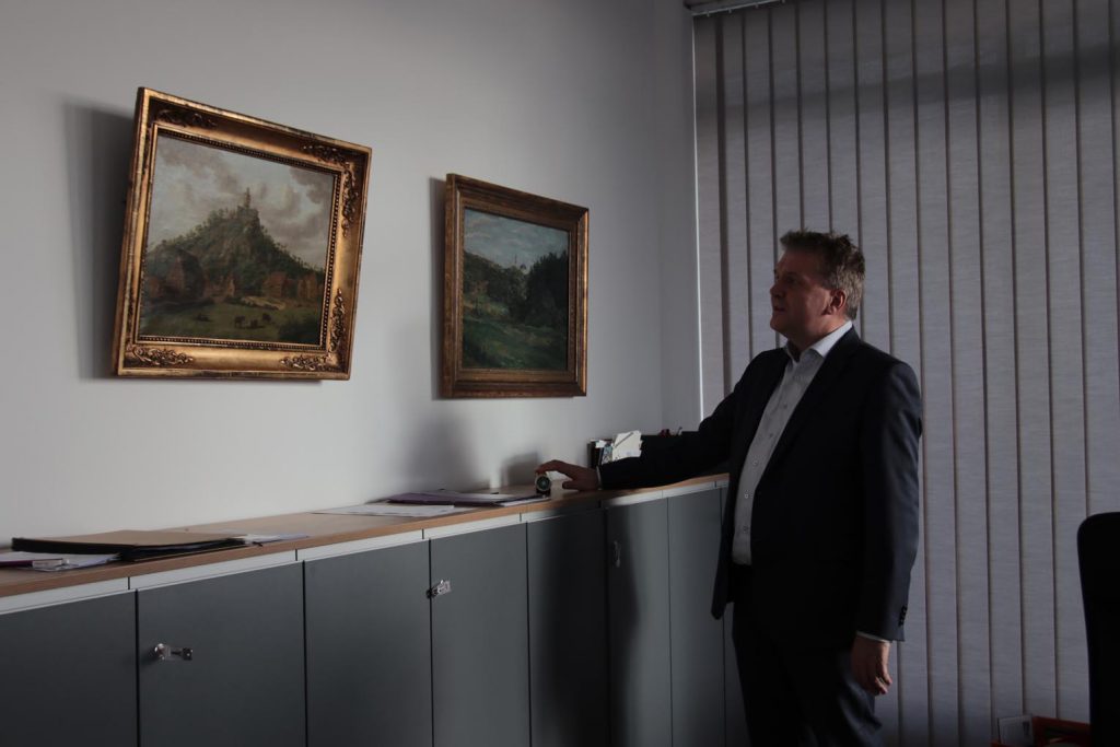 Der Landrat freut sich in seinem Büro über die romantisch idealisierende Ansicht der Burg Falkenstein von Johann Heinrich Rosenkranz und das Gemälde der Burg Kronberg von Wilhelm Trübner.