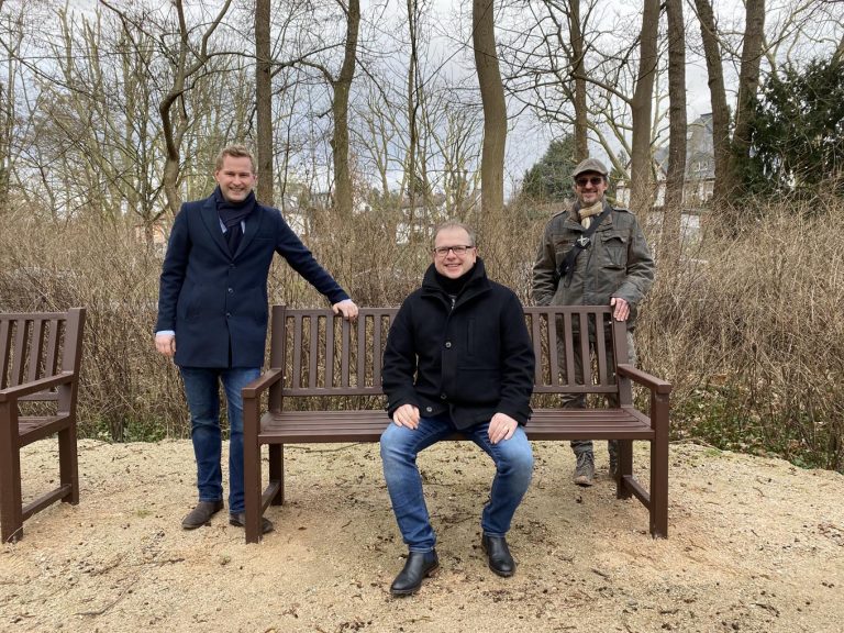 Bürgermeister Dr. Oliver Jedynak (v.l.), Kurdirektor Holger Reuter und Jens Pfeifer vom Produktbereich Grünflächen präsentieren die neuen Bänke im Jubiläumpark. - Foto: Stadt Bad Homburg